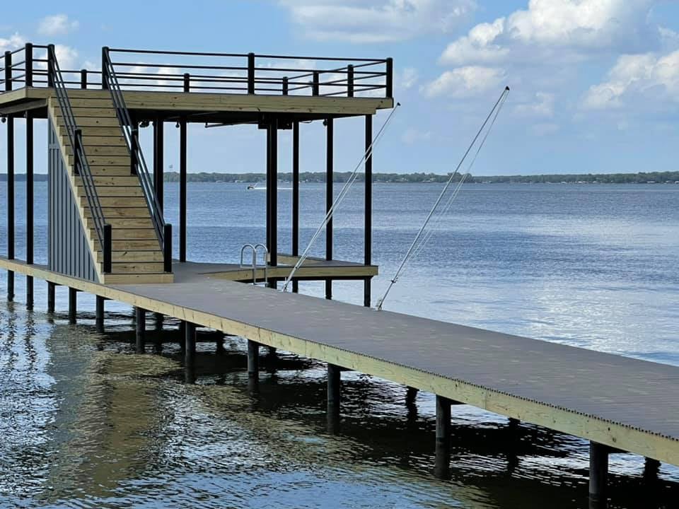 Deck pictured on the water with stairs leading to a top level deck, and down into the water